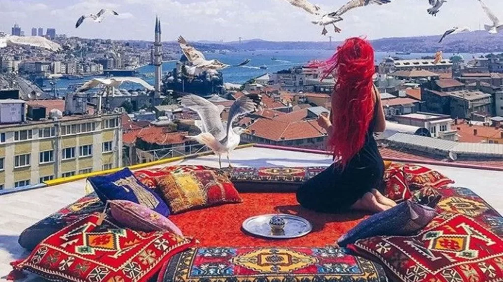 Eminönü çatısında Boğaz manzarasına karşı oturan kadın ve martılar