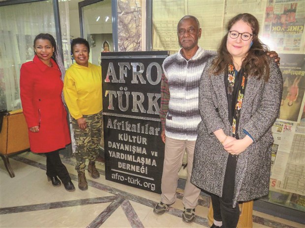 Afro-Türk Kültür Dayanışma Derneği pankartı önünde poz veren dört kişi