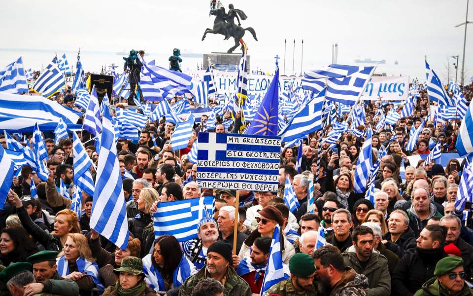 Yunan bayrakları taşıyan ve atlı heykel önünde toplanan kalabalık miting